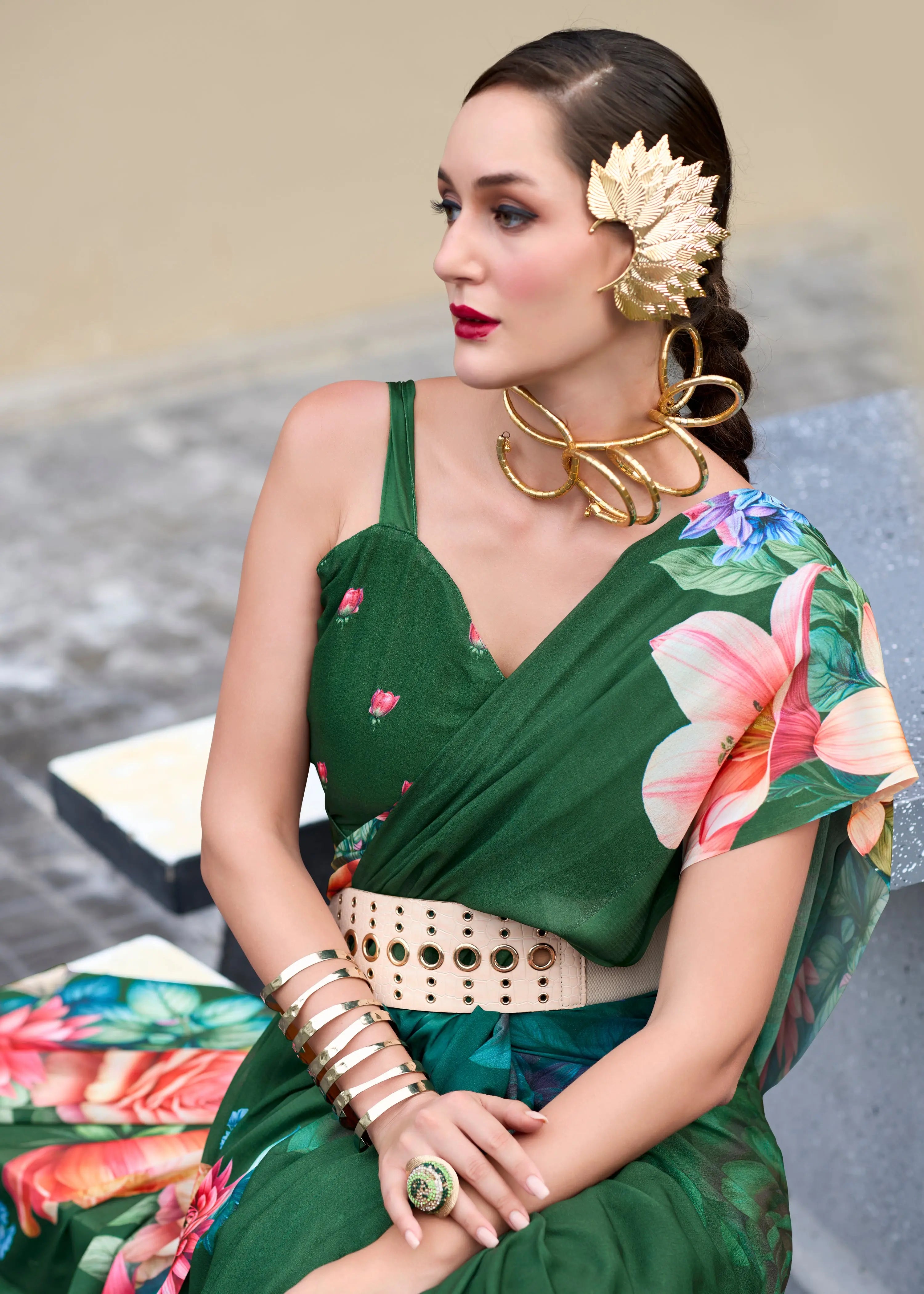 Woman in a green floral saree with gold jewelry and accessories.